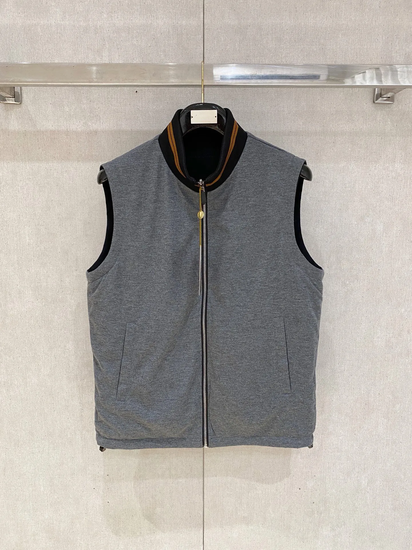 Loro Piana Reversible Stand-up Collar Vest Fabric: The front is made of high-elastic anti-wrinkle functional windproof fabric, which is smooth and waterproof, waterproof and stain-resistant, not easy to wrinkle, light and crisp; the back is made of worsted wool knitted fabric, which is soft to the touch and skin-friendly, breathable and constant temperature, one pair of fabrics, taking into account outdoor practicality and home leisure comfort, it is an old-money classic Italian commuter fabric. Design highlights: Double-wear dual-style design, the functional side is smart and business-like, and the knitted side is soft and elegant, allowing you to switch between two atmospheres when wearing one set; The brand logo is embroidered with the same color on the left chest, which is low-key and subtle, unobtrusive and highlights the texture; Brown trim strips are spliced ​​on the side of the pocket, with metal snaps, and the light luxury details are full; The collar is closed with contrasting brown and yellow striped ribs, and the hem has drawstring adjustments on both sides to tighten the fit. Version and structure: Improved high stand-up collar tailoring, fits the neck without getting stuck, and modifies the shoulder and neck lines; Slightly loose straight cut, accommodates all body shapes, can be worn with shirts, polo, and thin knitted fabrics without restraint; Symmetrical welt pockets with metal snap buckles for stable storage of items and preventing them from slipping. Style positioning: Light business commuting, Premium casual, outdoor travel wear, minimalist, low-key and noble, Versatile is a must-have item for mature men. Color: Black, Navy Blue (the reverse side is Gray knitted surface) Sizes: M-4XL